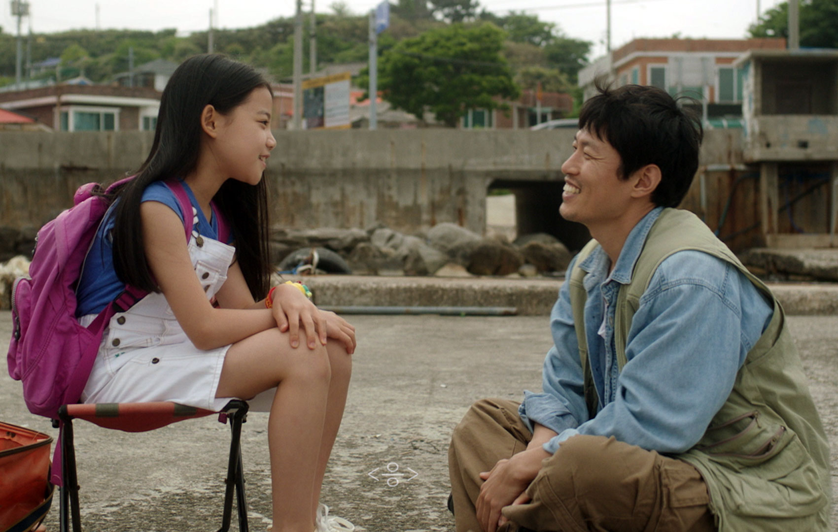 Koreanisches Mädchen sitzt ihrem lächelnden Papa auf Augenhöhe gegenüber.