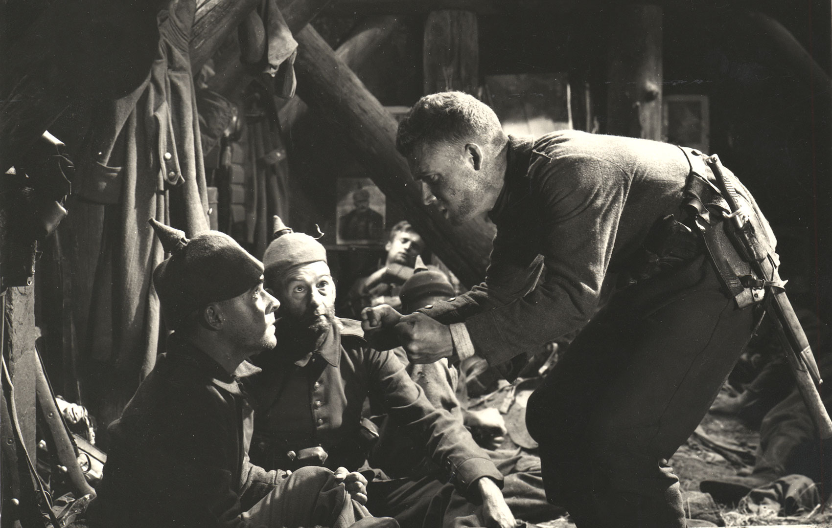 Schwarz-Weiß-Bild: Männer in Uniform des Ersten Weltkriegs sitzen in einm Kriegslager und unterhalten sich.