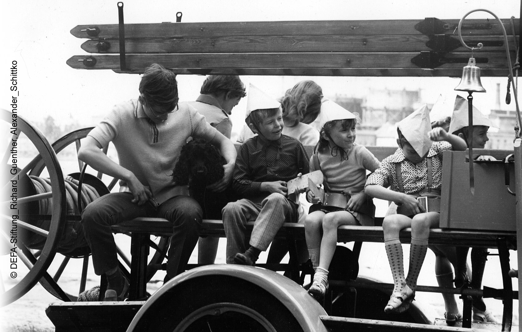 Kinder und Jugendliche sitzen gemeinsam auf einem alten Feuerwehrauto.