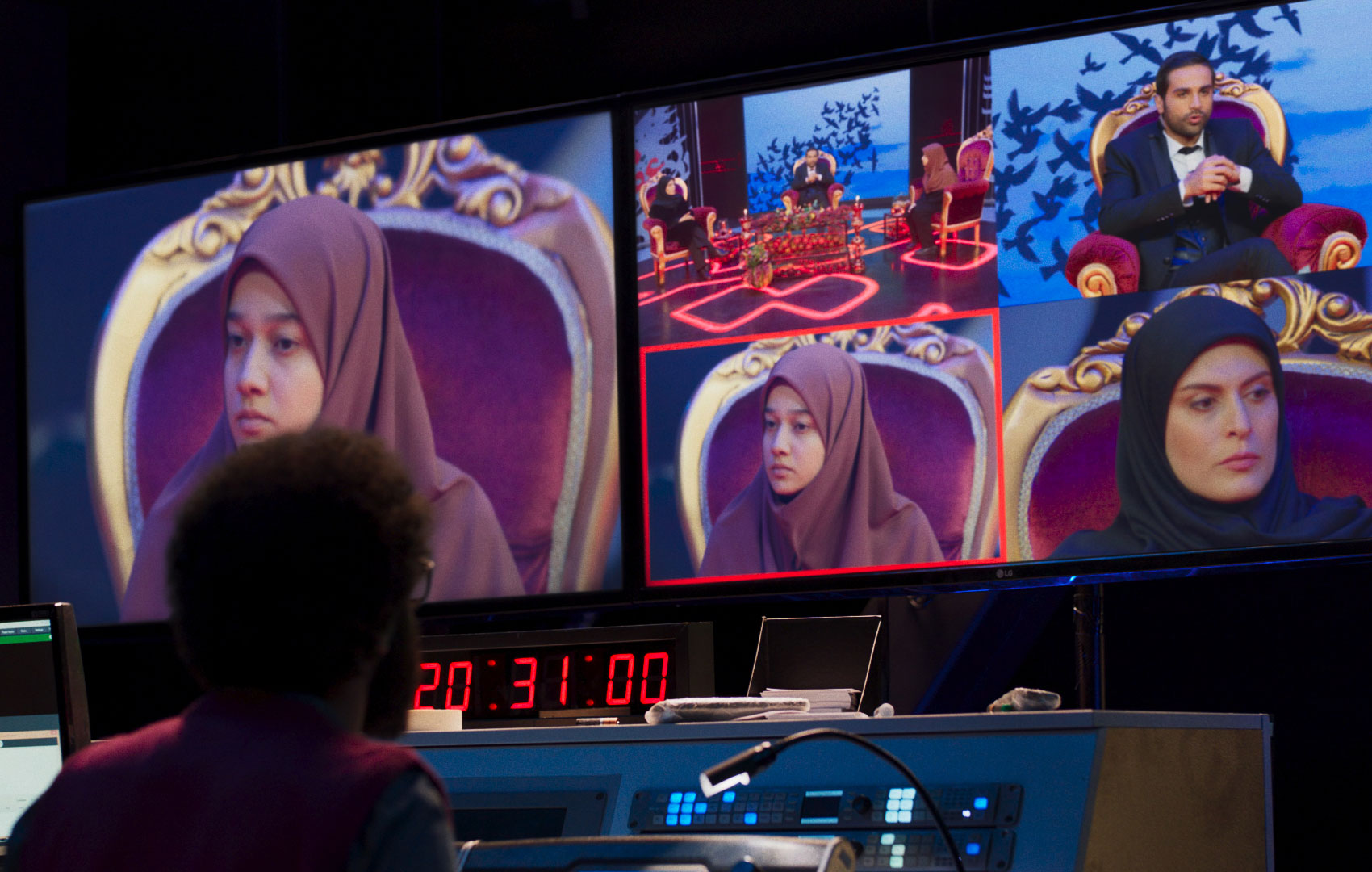 In der Regie im Backstage-Bereich eines Fernsehsenders schaut sich ein Mitarbeiter auf einem Bildschirm verschiedenen Kameraeinstellungen der Gäste einer Sendung an.