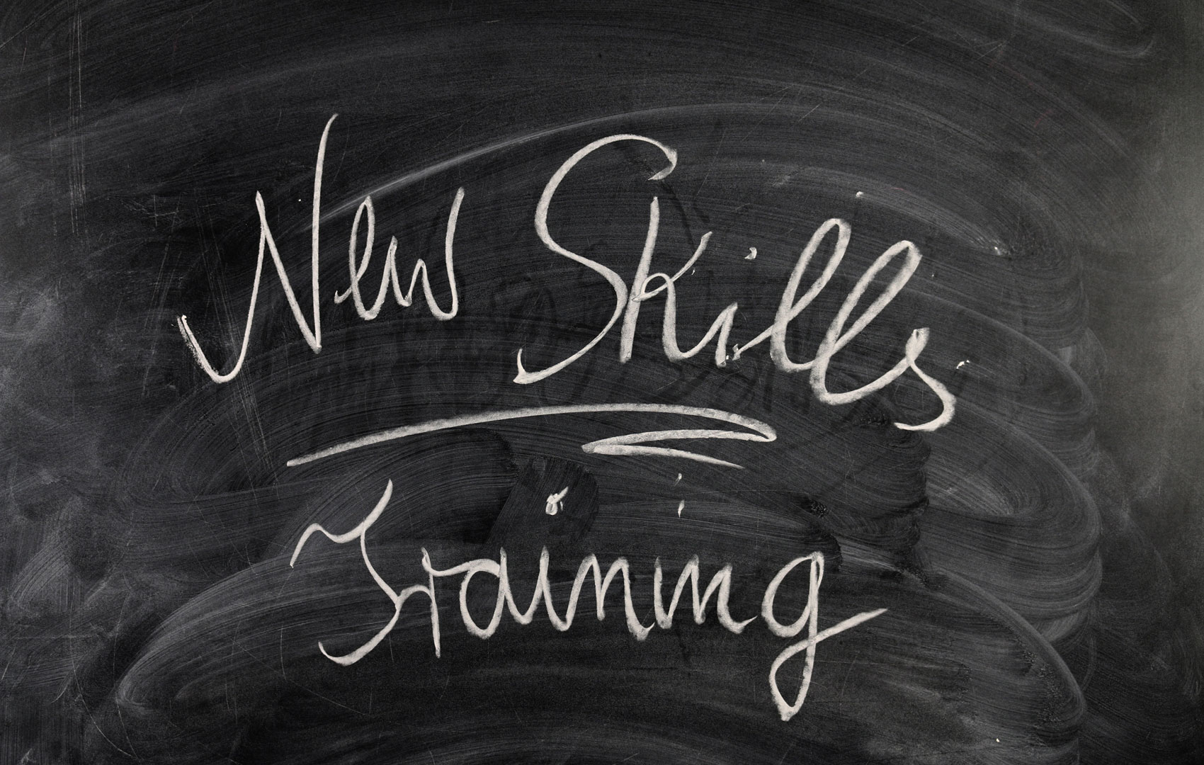 Auf einer Schultafel steht: New Skills, Training