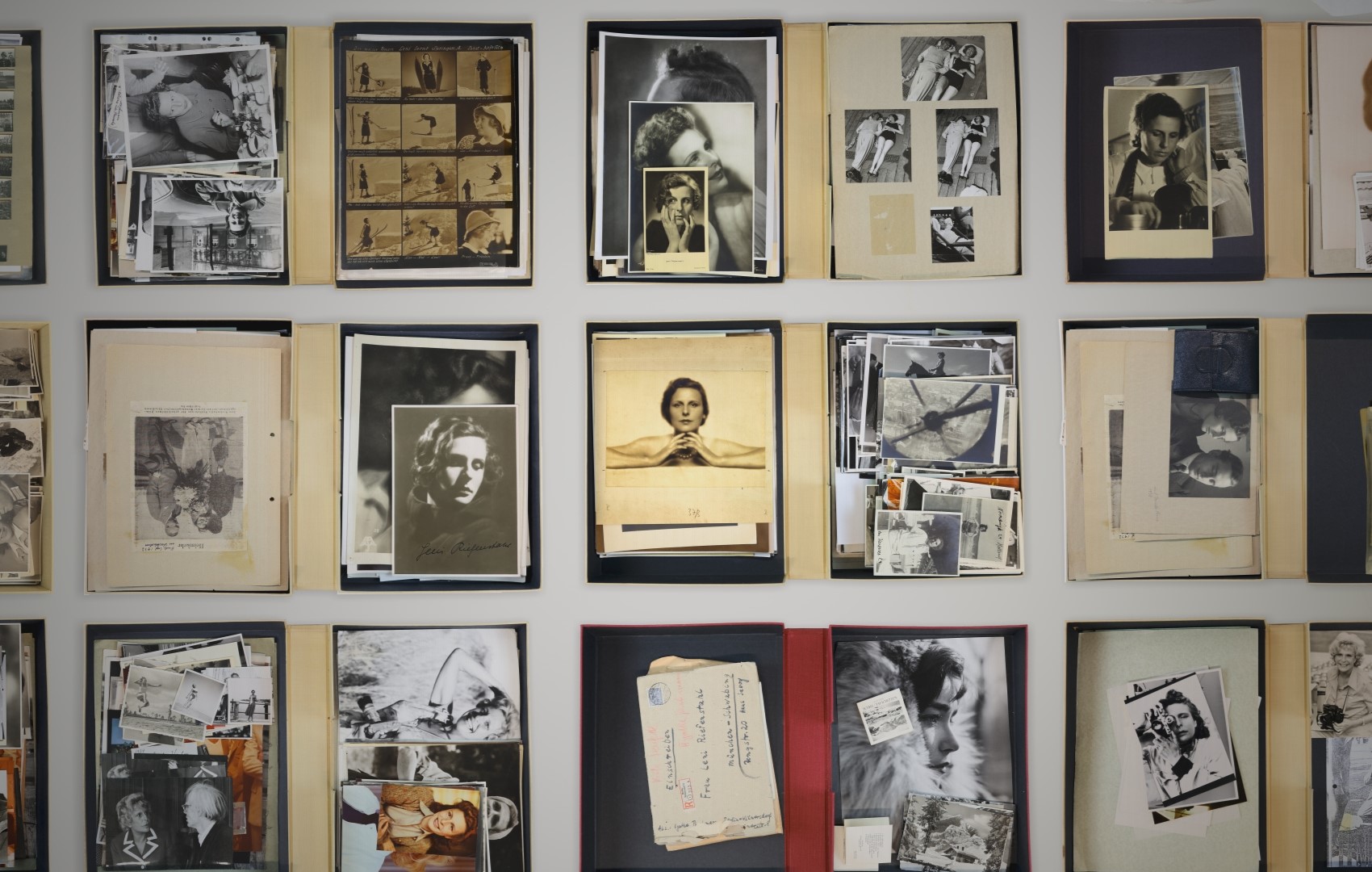 Eine Wand voller Dokumente und Fotografien, welche die Regisseurin Leni Riefenstahl zeigen.