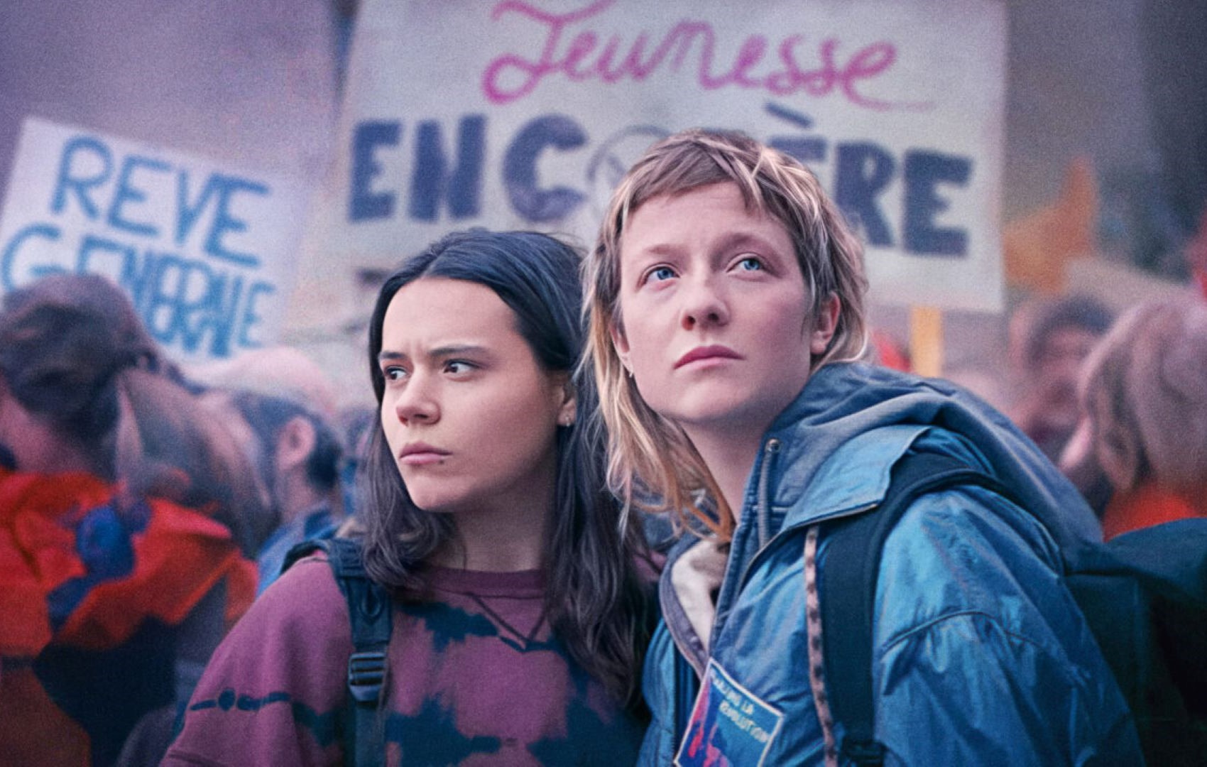 Zwei junge Frauen sind auf einer Demonstration. Beide schauen an dem Betrachter vorbei.