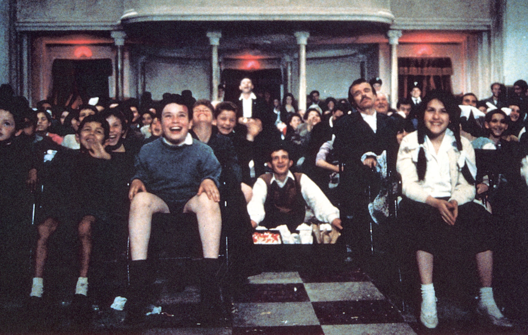 Ein Blick in einen Kinosaal aus Richtung der Leinwand: Menschen gemischen Alters sitzen auf Stühlen, im Gang oder stehen im hinten im Saal. Alle lachen und freuen sich.