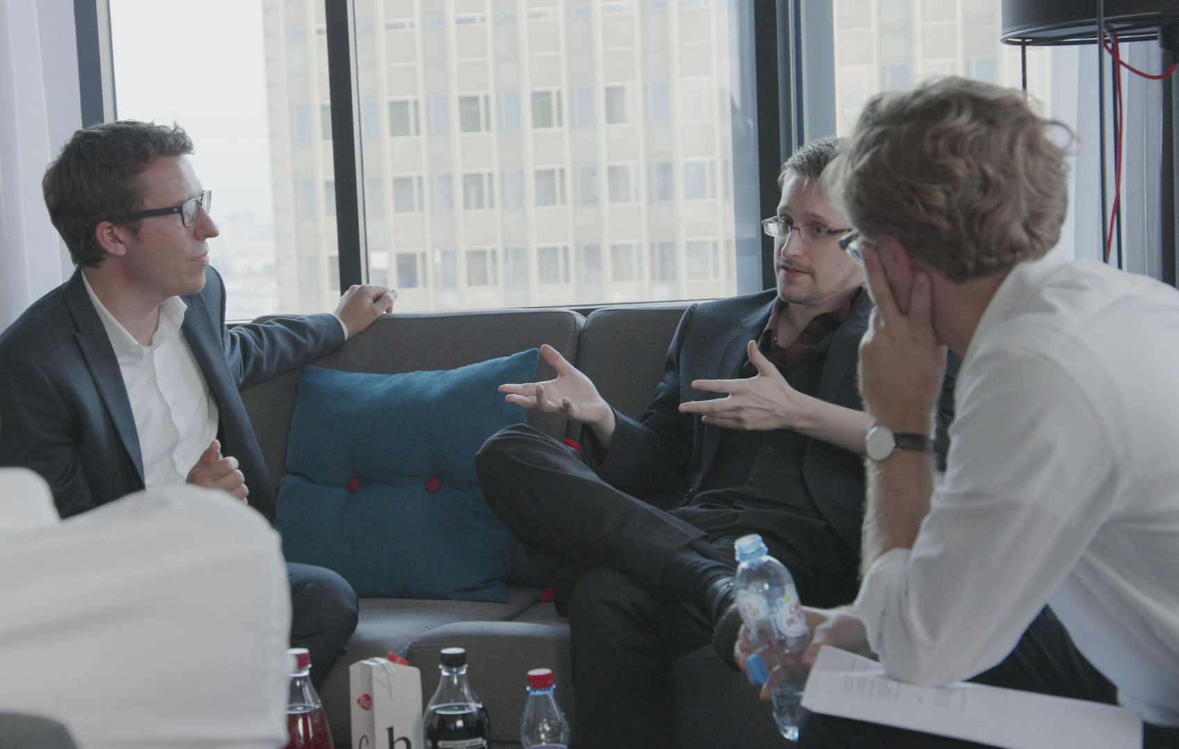 Drei Männer sitzen auf einer Couch und diskutieren miteinander. Sie sind einander zugewandt und hören sich gegenseitig zu.