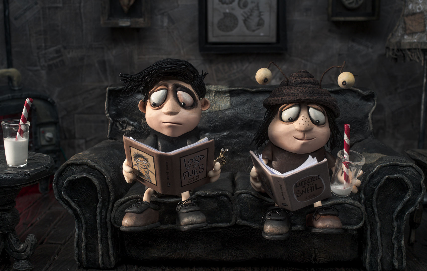 Puppentrick-Animation: Zwei Perosnen sitzen auf einem Sofa und lesen. Eine hat einen Hut mit Schneckenaugen an.